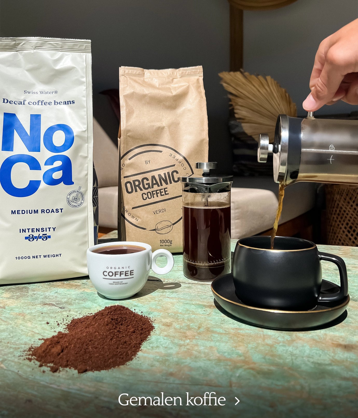Ground coffee from Organic Coffee with a French press and black ceramic cup on a green tabletop